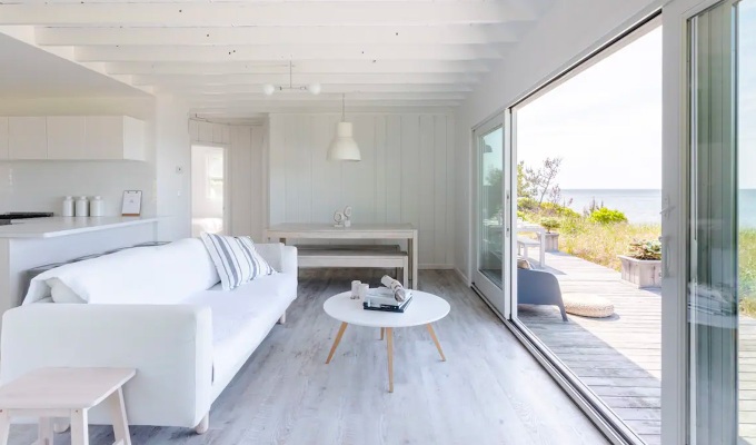 Best Airbnbs in the Hamptons - A bright, minimalist living room that has a patio that looks out onto the ocean.