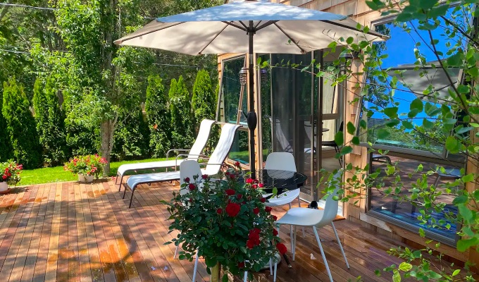 Best Airbnbs in the Hamptons - The backyard of a Hamptons home featuring patio furniture, an umbrella and flowers.