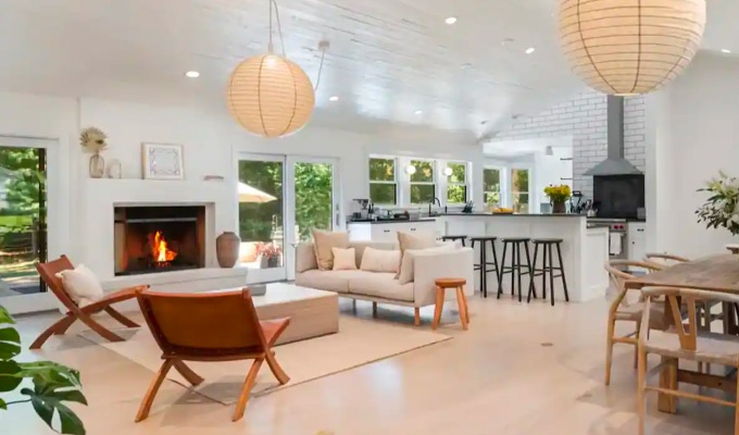 Best Airbnbs in the Hamptons - A modern living room with seating, a couch, bright lighting and a kitchen breakfast bar.