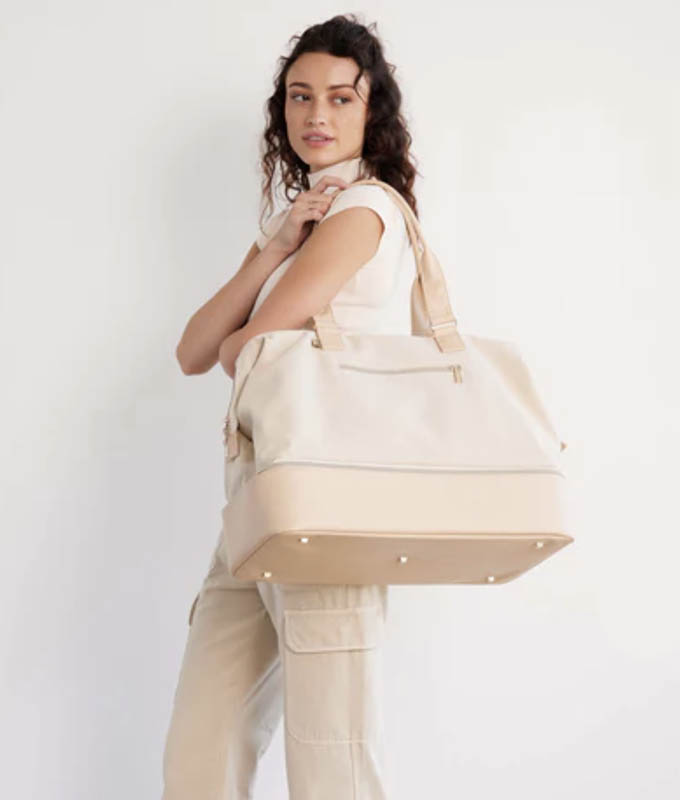 best-luggage-brands: woman carrying Beis weekender bag