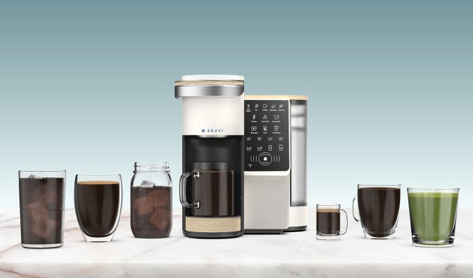 bruvi review: bruvi single-serve coffee machine on counter surrounded by coffee and espresso drinks