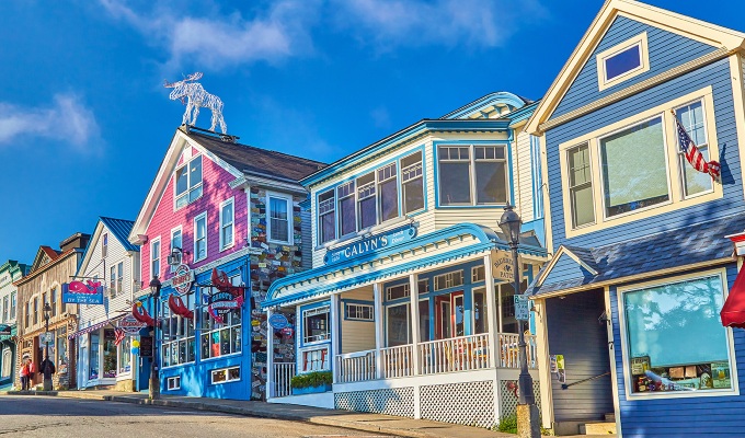 Places Like the Hamptons - A colorful facade of buildings in downtown Bar Harbor. The sky is mostly clear with a few clouds.