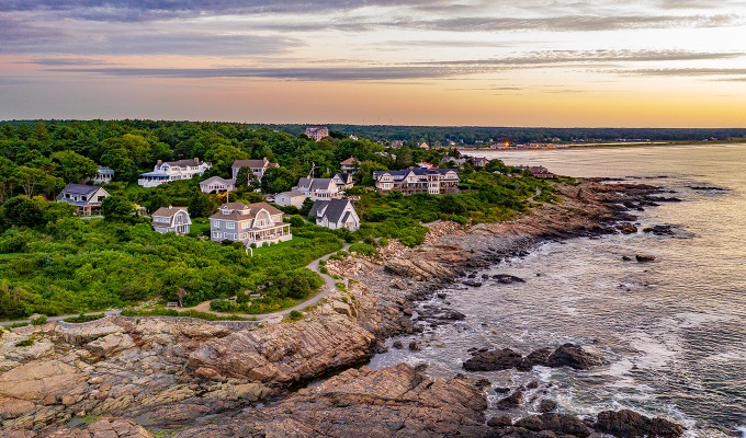 Places Like the Hamptons - A rocky shore with homes on it that looks out onto the ocean during sunset.