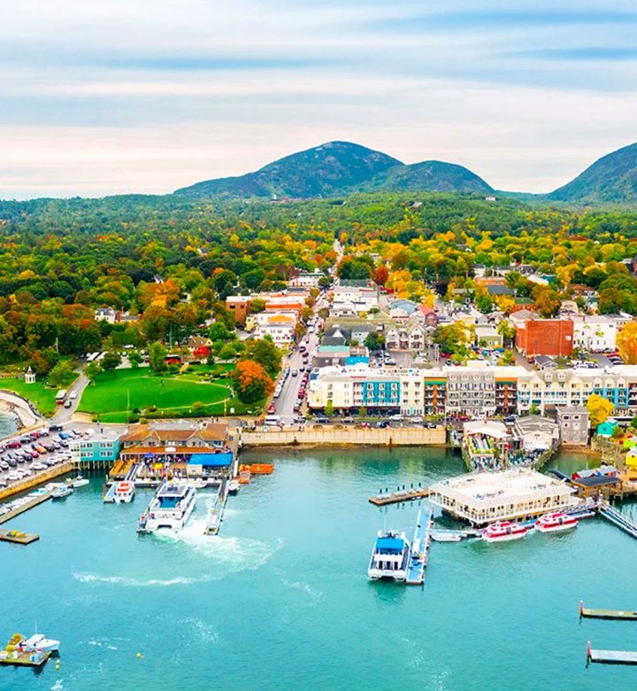 Places Like the Hamptons - An overhead shot of an inlet at Bar Harbor in Maine. There are boats, docks and colorful houses on the shore. The water is clear and the sky is bright.