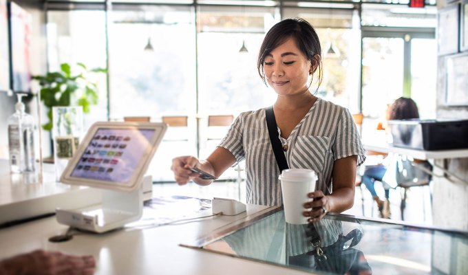 restaurant trends 2023: woman paying for coffee at a cafe with a card