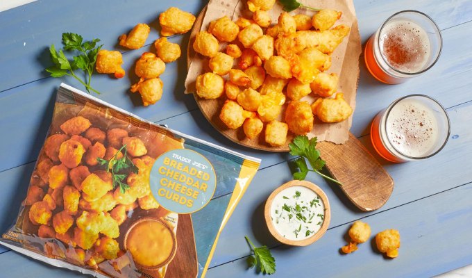 new at trader joe's june 2023: breaded cheddar cheese curds on a plate with two glasses of beer next to them