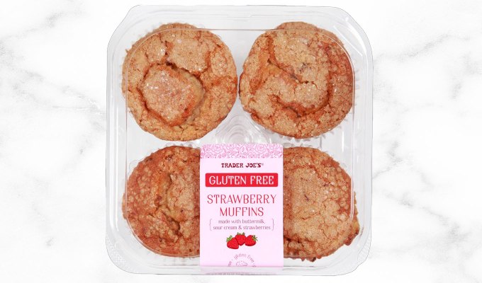 new at trader joe's june 2023: plastic container of gluten-free strawberry muffins on a marble background