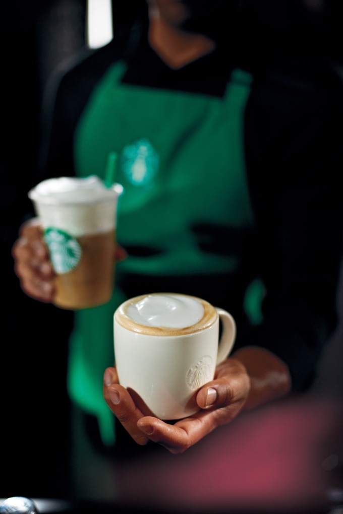 vegan at starbucks: a barista holding two coffee drinks